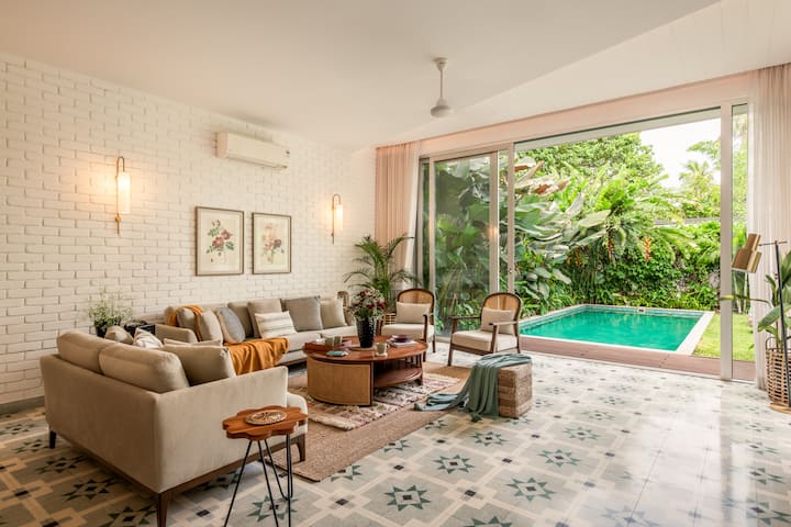 Spacious, air-conditioned living room with comfortable seating, a smart TV, music speaker, an adjoining dining area, and direct access to the private pool.