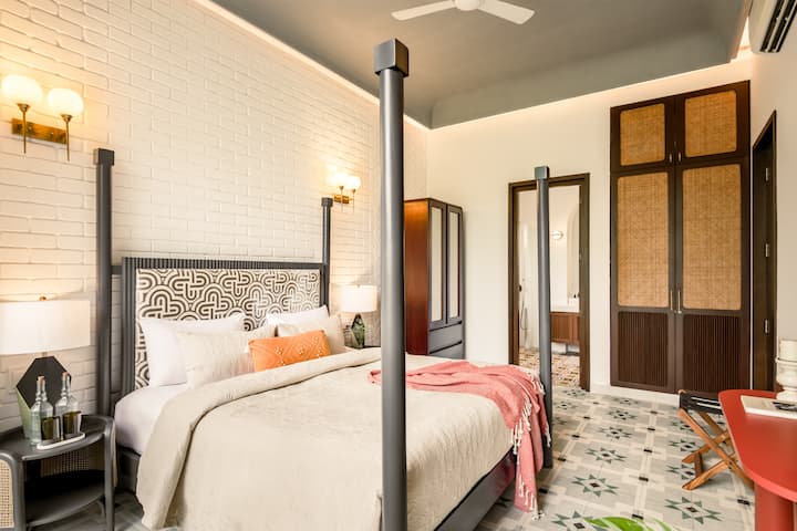 Bright bedroom with a king-size bed, attached ensuite bathroom, and pool access.