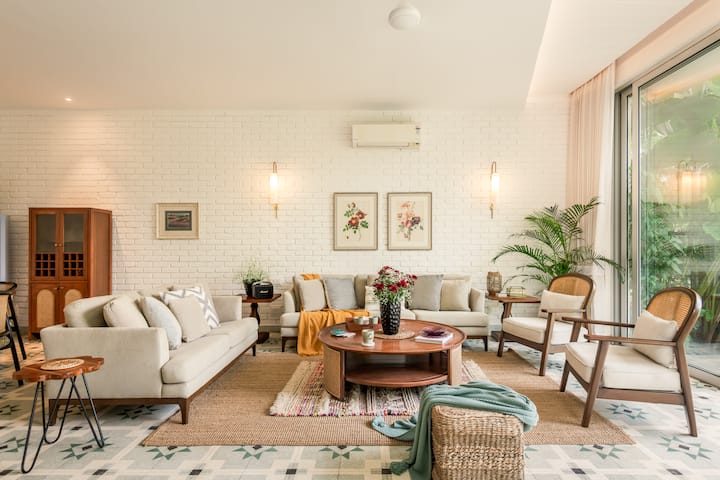 Spacious, air-conditioned living room with comfortable seating, a smart TV, music speaker, an adjoining dining area, and direct access to the private pool.