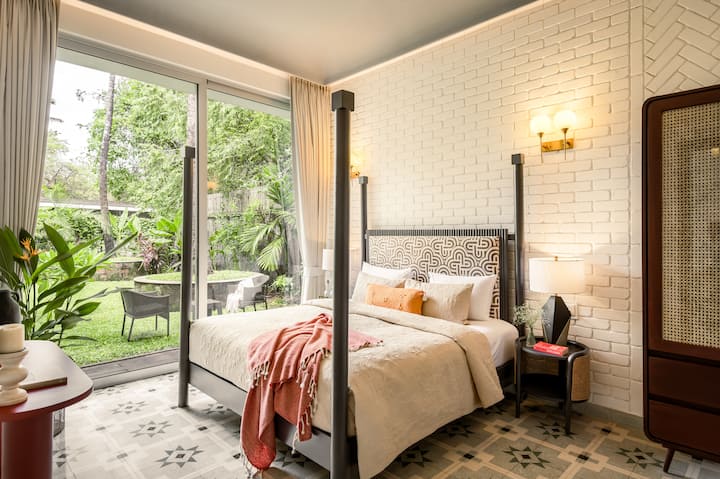 Bright bedroom with a king-size bed, attached ensuite bathroom, and pool access.