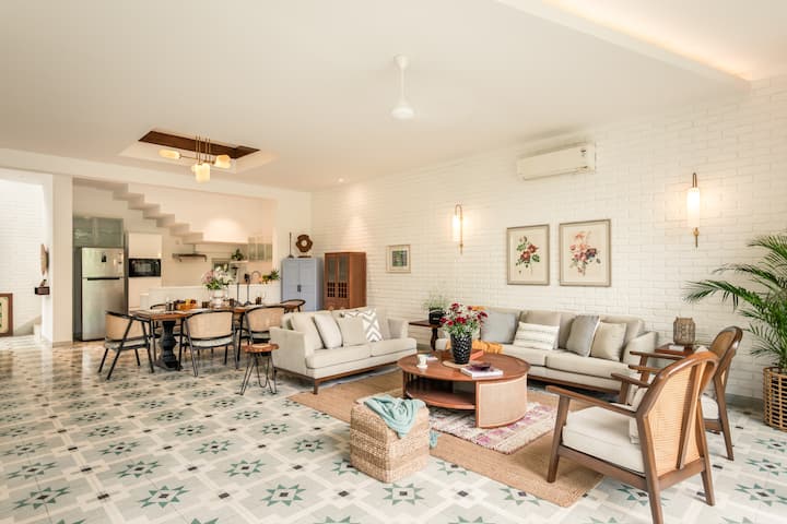 Spacious, air-conditioned living room with comfortable seating, a smart TV, music speaker, an adjoining dining area, and direct access to the private pool.