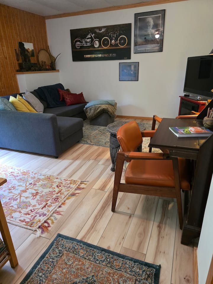 Salon inférieur avec télévision et canapé-lit. Il y a de la literie dans la partie rabattable du sofa. Profitez du secrétaire antique pour écrire ou dessiner, ou tout simplement pour vous installer confortablement et regarder la télévision. Le chauffage électrique sous le téléviseur ajoute de la chaleur supplémentaire.