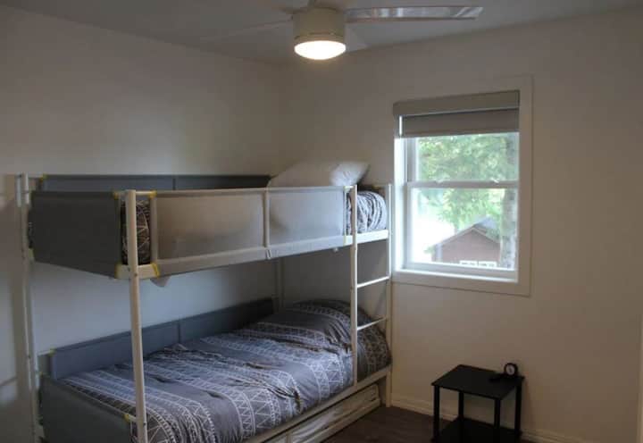 Second bedroom with a bunk bed and pull-out trundle, ideal for children or extra guests. Includes a ceiling fan, spacious closet, and a beautiful view of Long Lake from the window.