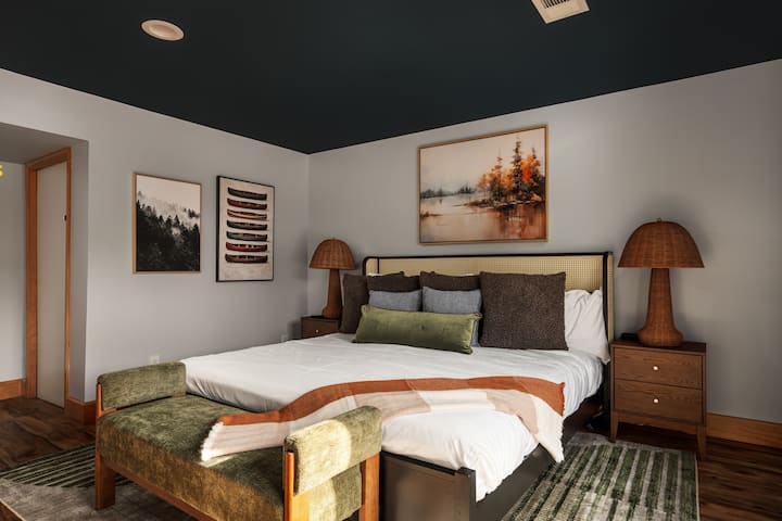 Recharge in the spacious downstairs king bedroom with layered bedding, warm wood details, and a calm, comfortable feel.