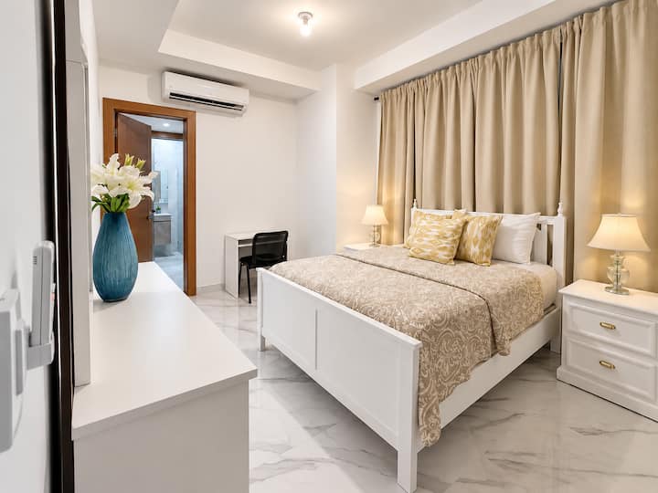 Chambre confortable et accueillante avec lit queen size, climatisation, espace de travail et accès direct à la salle de bain privée.