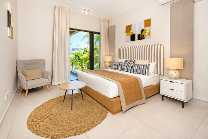 Chambre 1 avec lit double, tête de lit cannage rayée, déco colorée et accès à la terrasse avec vue sur le jardin.