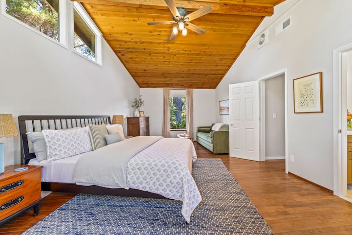 Suite principale spacieuse avec un très grand lit, un canapé-lit, des plafonds voûtés en bois, un coin salon confortable et une salle de bains privée attenante.