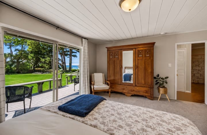 Chambre spacieuse avec très grand lit, une belle armoire, une vue sur l'océan et un accès direct à la terrasse par une porte coulissante en verre.