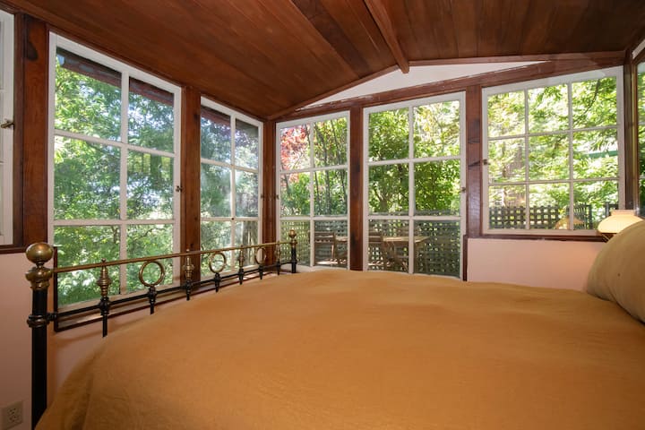 Chambre avec literie dorée chaleureuse et vue panoramique par la fenêtre.