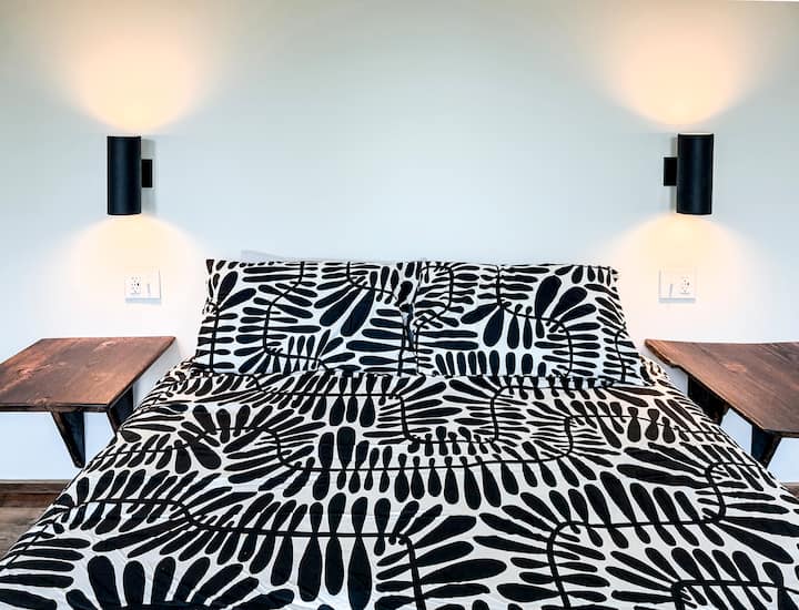 The guest bedrooms offer comfortable queen memory foam beds and a wall of windows (not shown). Each person has their own custom-designed floating white-oak side table, reading light, and USB/USB-C power adapters to charge all of their devices.