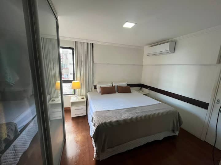 ห้องนอนที่สะดวกสบายพร้อมเตียงคิงไซส์และระบบนวด เครื่องปรับอากาศ ทีวี ม่านทึบ และโต๊ะข้างเตียง ไม่มีตู้ที่มีประตูกระจก ในตู้เสื้อผ้ามีชั้นวางไม้แขวนเสื้อให้ผู้เข้าพักใช้
