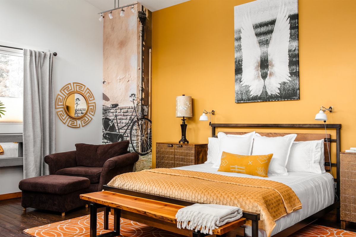 An inviting & unique master bedroom with private lounge area. Bicycle wall mural sits in a corner and angel art rests above bed.