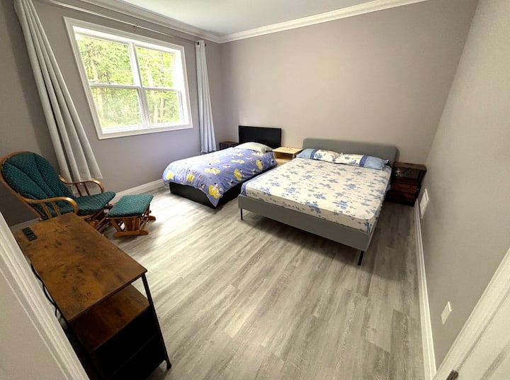 Chambre 1 · Chambre principale au rez-de-chaussée. Cette chambre spacieuse dispose de deux lits séparés, de tables de chevet, d'une commode et d'une grande fenêtre donnant sur les arbres. Elle est idéale pour les familles ou les voyageurs qui préfèrent des lits séparés.