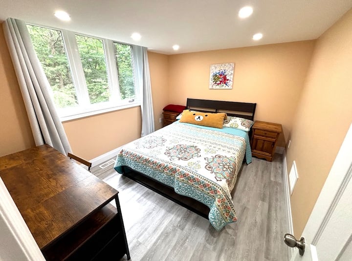 Chambre 3 · Étage supérieur. Une pièce fermée et confortable avec un lit, des tables de chevet, une commode et une grande fenêtre donnant sur les arbres environnants.
