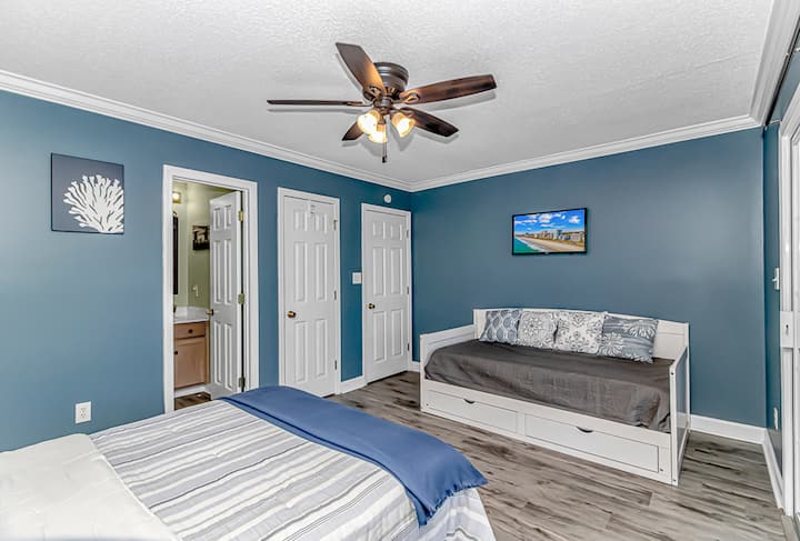 Coastal blue bedroom with daybed, storage, and ensuite bath access