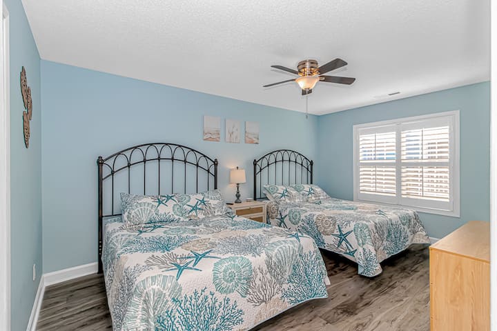 Bright coastal bedroom with 2 queen beds and relaxing beach-style decor