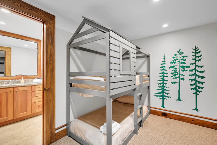 Charming bunk room with playful tree mural and ensuite bath access