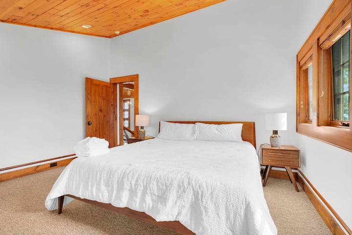 Bright, cozy bedroom with king bed, warm wood accents, and natural light