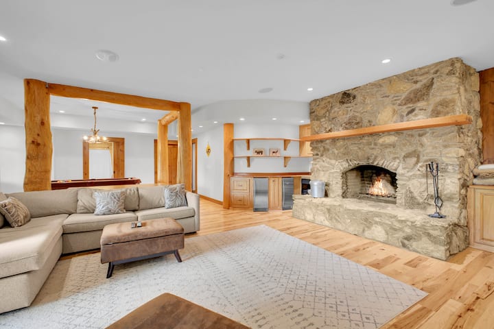 A second stone wood-burning fireplace anchors cozy nights downstairs, with a wet bar close by for topping off your drink.