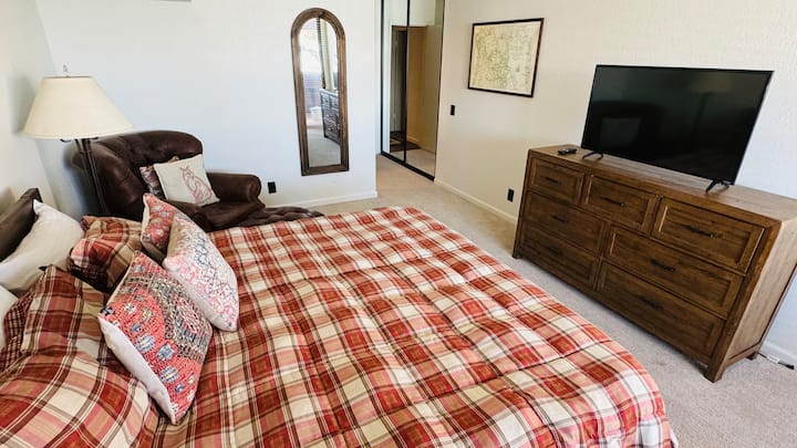 Glavna spavaća soba s bračnim krevetom, kožnom stolicom i televizorom.