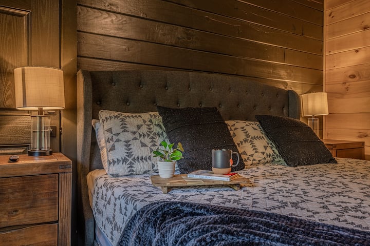 The master bedroom on the main floor has a king bed with warm lighting and cabin-style charm