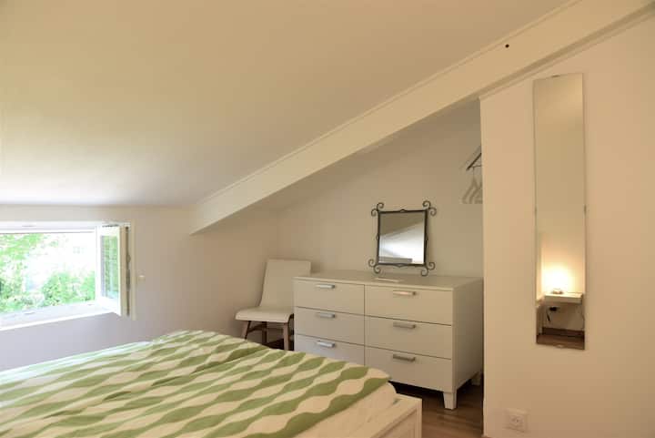 Acogedora recámara en el piso superior con una cama tamaño queen, tocador, estantes y espacio de almacenamiento en los cajones de la cama. Techo bajo en algunos lugares. La habitación está equipada con aire acondicionado. Mosquiteros y persianas en las ventanas.
