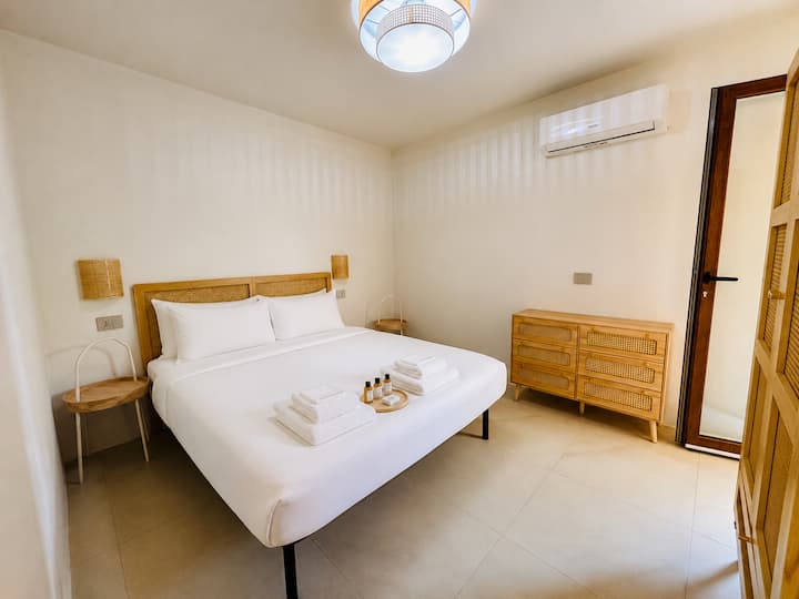 dormitorio principal doble con aire acondicionado, armarios y, a la derecha, una ventana francesa que conduce directamente al patio amueblado de la casa