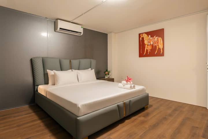 ห้องนอน 4 มีเตียงขนาดคิงไซส์ การออกแบบที่ทันสมัยและเรียบง่ายด้วยโทนสีเทา – ขาวนวล – น้ำตาลไม้ เตียงหุ้มเบาะพรีเมียม เมื่อผสานเข้ากับแสงไฟที่อบอุ่นและงานศิลปะ จึงสร้างพื้นที่ส่วนตัวที่อบอุ่นและสะดวกสบาย