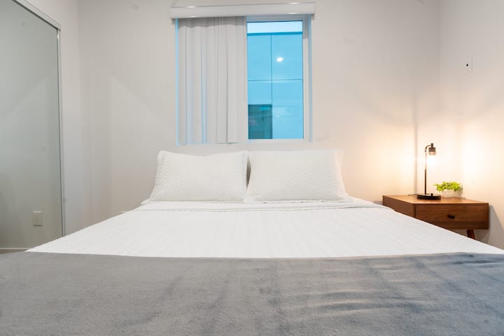 Une table de chevet et une lampe gardent vos essentiels à portée de main, tandis que le placard avec miroir offre un espace de rangement pratique.