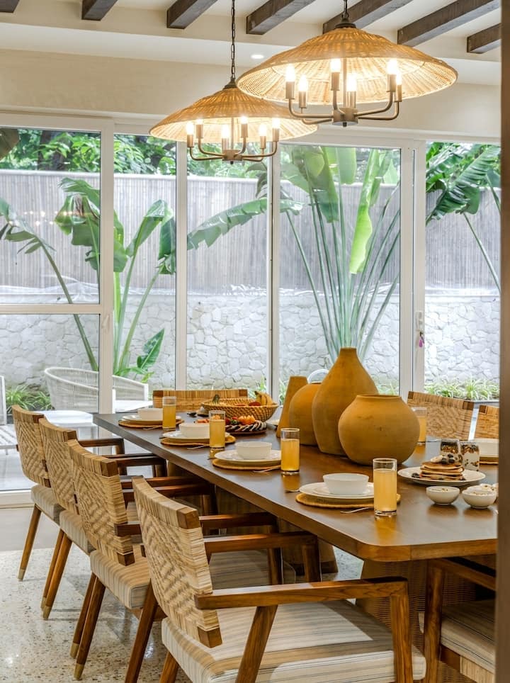Dining table seats ten, with the living room and pool beyond. No one eats standing at the counter in this house.