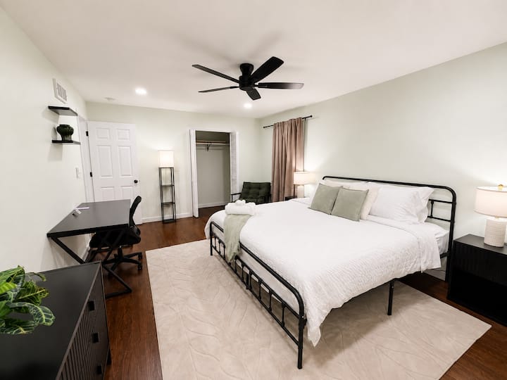 Dormitorio principal en la planta baja con cama tamaño king, escritorio para computadora y sillón. La habitación incluye un baño completo.