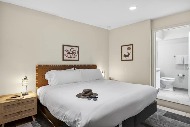 Unwind in a serene king bedroom designed with warm accents, plush bedding, and a calming modern aesthetic.