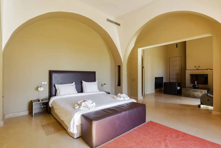 Ensuite bedroom at Villa Tameslohte with a double bed in white linen set beneath broad plaster arches