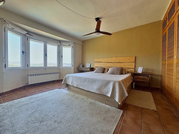 Dormitorio principal con cama doble, ventilador y vistas.