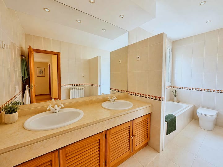 Baño principal con bañera y dos lavabos sobre mueble de madera.