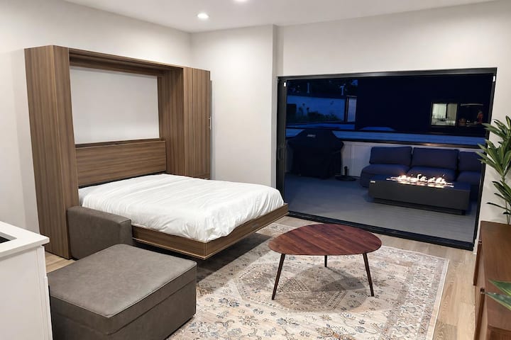 Estudio moderno con cama abatible, patio con fogata y una transición fluida entre los espacios interiores y exteriores