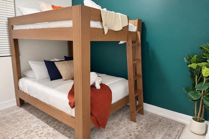 Habitación elegante con litera, pared decorativa en color azul turquesa y ropa de cama acogedora lista para los huéspedes