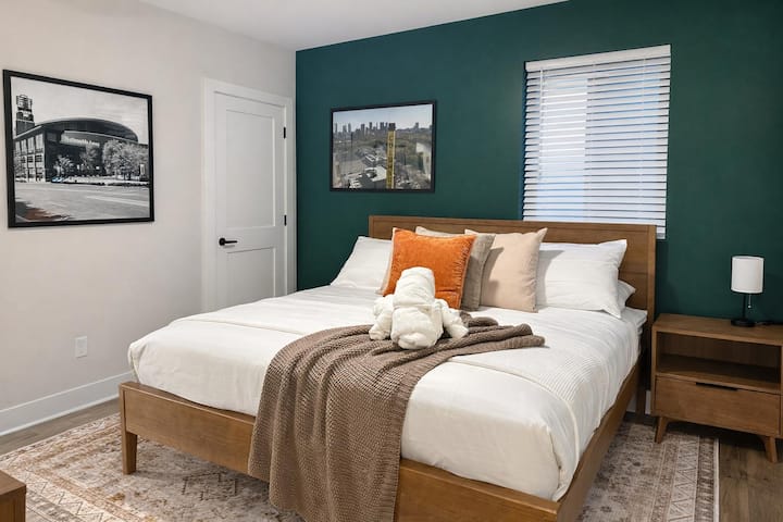 Elegante recámara con cama tamaño queen, pared decorativa en color azul turquesa y toques modernos y acogedores.