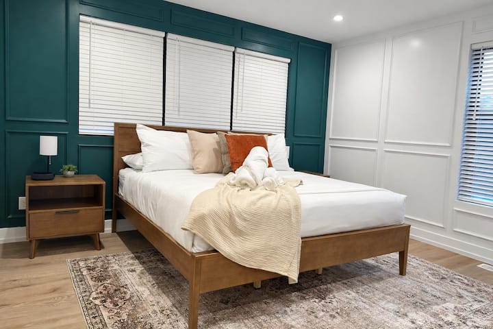 Elegante dormitorio con pared decorativa en color azul turquesa, cómoda cama tamaño king y acabados modernos.