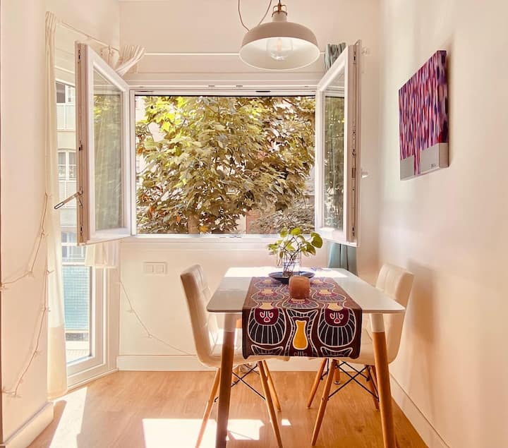 Comedor luminoso junto a una ventana abierta al arbolado.