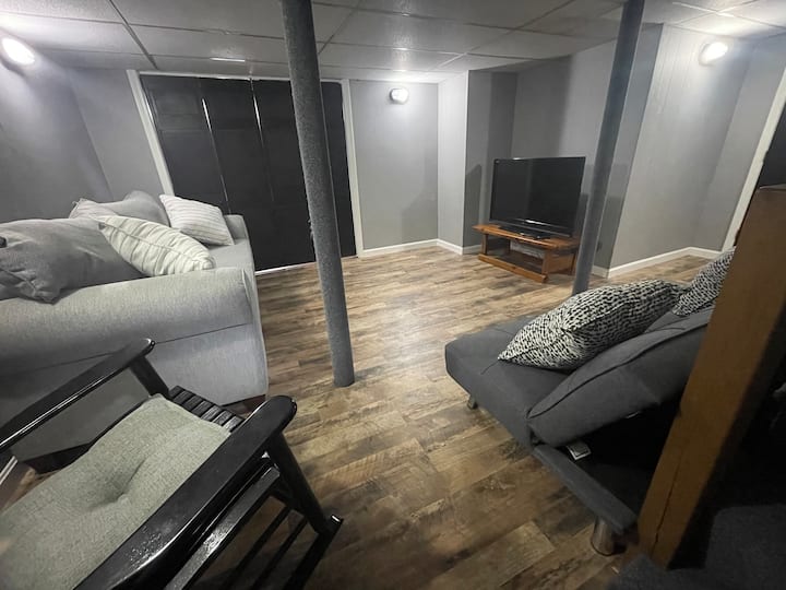 地下室设有另一台智能电视、一张标准双人床和双人日式床垫、小桌子和一些重量和健身垫。