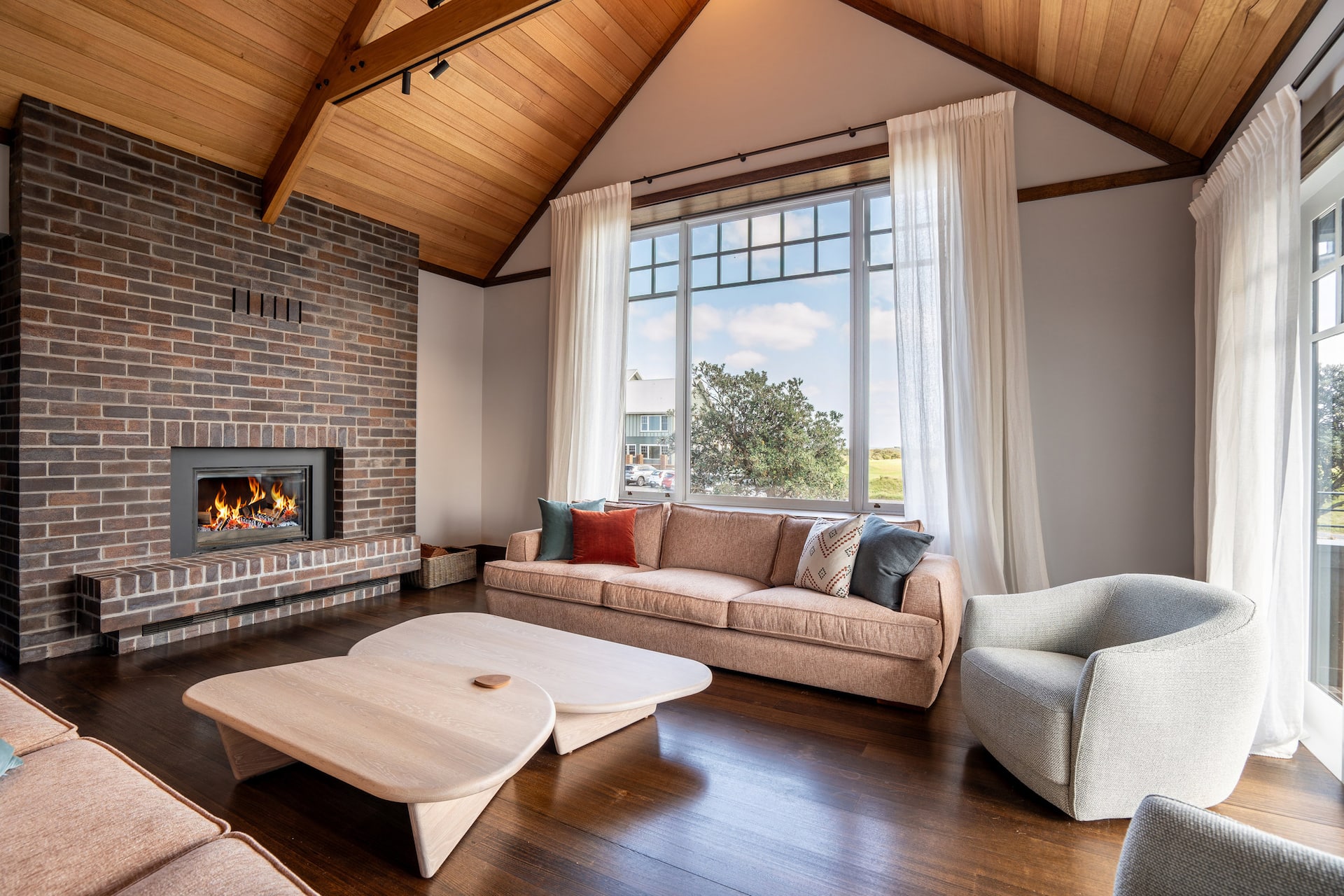 Golf Links Lodge living room with vaulted timber ceiling, fireplace and golf course outlook