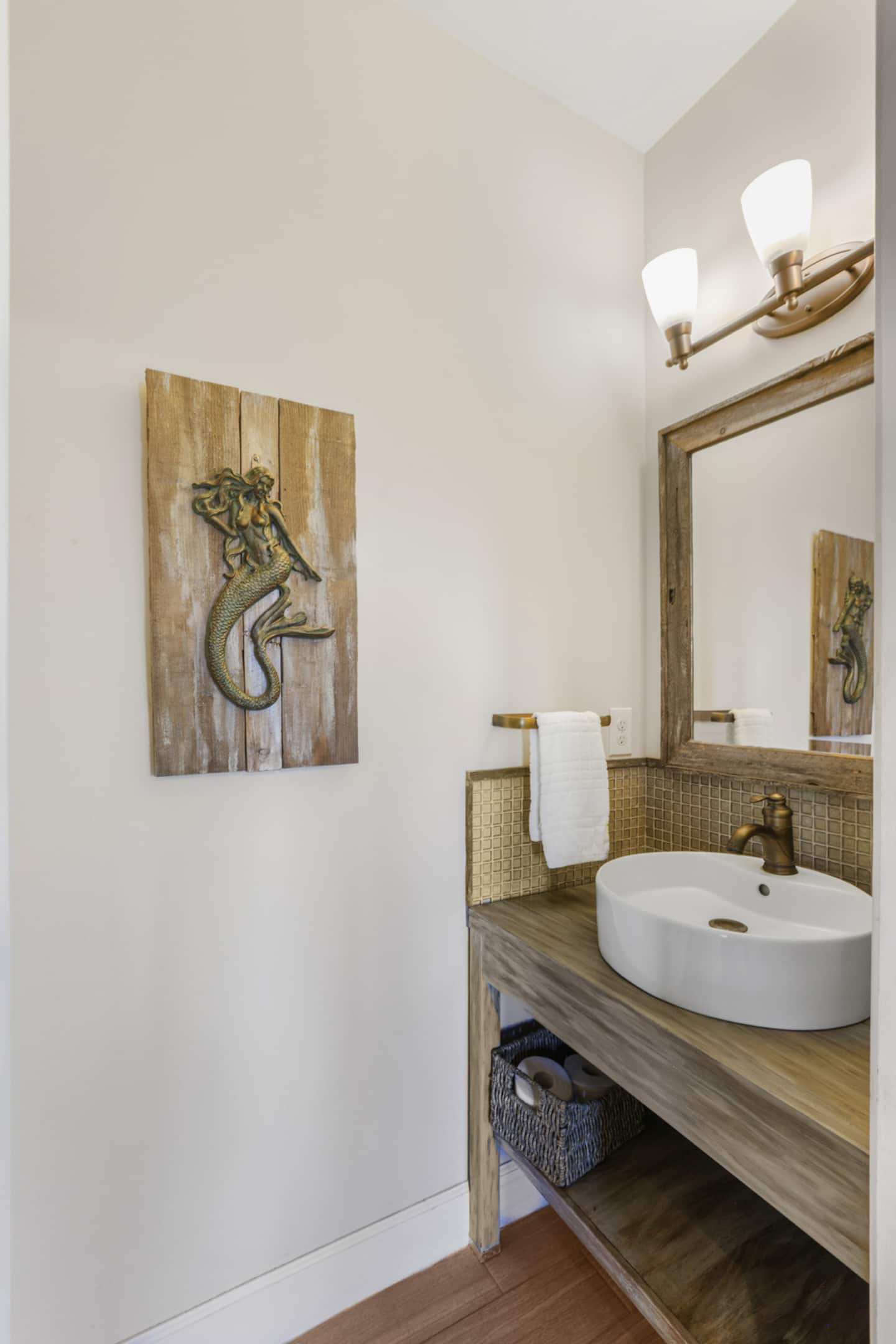 Wash up at the vessel sink under the mermaid art: the powder room right off the main floor, so nobody has to invade the privacy of the king room.
