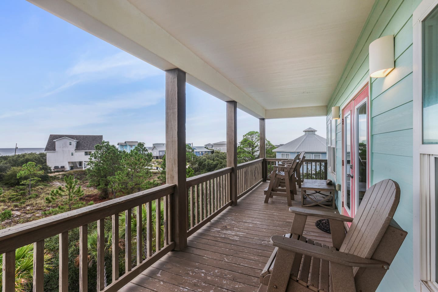 Bring your morning coffee to the upper balcony and watch the neighborhood wake up: shade overhead, breeze coming through, the beach houses stacked out toward the Gulf.