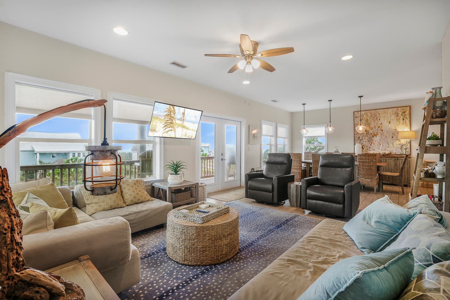 Spread out after a beach day: someone on the sectional, someone at the table, the deck doors open to the breeze. One big open room, so nobody misses the story.