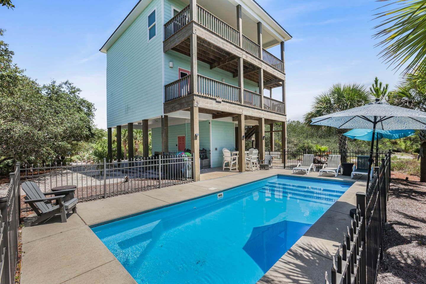 Pull in, drop the bags, and you're steps from the water: three stacked porches above, the pool right at the foot of the stairs.