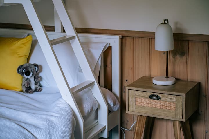 Cama matrimonial abajo, cama individual arriba. Una mesita de noche y una lámpara de lectura.