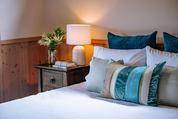 Cama tamaño queen con ropa de cama cómoda y sábanas lujosas. Flores frescas del jardín, lámparas de lectura, mesitas de noche con cajón y armarios.