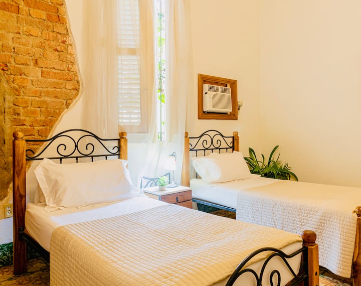 Chambre spacieuse, digne de Pinterest avec lit confortable, climatisation, ventilateur et coffre-fort. Lumineux et aéré, avec une immense fenêtre de 1927 qui met en valeur les charmants détails originaux du bâtiment.