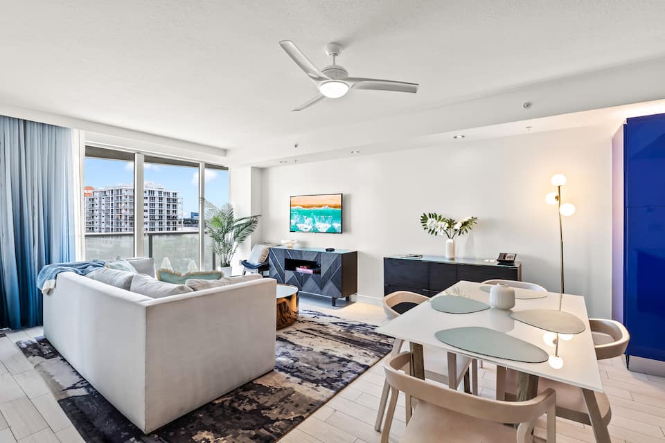 Wide living-room view with the closed sofa, dining table, and balcony